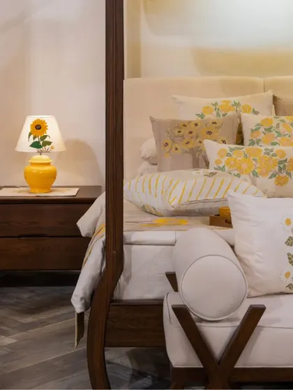 A close-up of the bedside, where a custom lamp with a sunflower motif complements the yellow tones of the hand-embroidered linens by Gaurang Home.