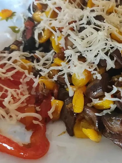 A delicious mix of pan-grilled mushrooms, corn, and bell peppers, topped with grated cheese. A perfect appetizer for any party.
