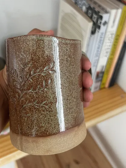 Holding this hand-built mug, you can feel the delicate, imprinted texture of a leafy branch.