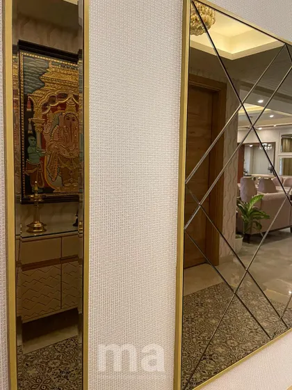 A detail shot of the foyer's accent wall, featuring a large, tinted mirror with a geometric bevelled pattern. The mirror not only adds a decorative touch but also reflects the living space, making the hallway feel wider.