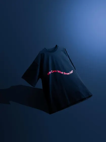 A minimalist shot of a t-shirt against a deep blue background. The simple, clean lighting and composition make the red text pop, creating a bold and graphic image.
