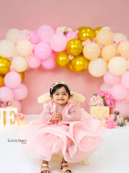 A picture of pure happiness. This little girl's radiant smile captures the excitement of her first birthday celebration in our pink and gold studio setup.