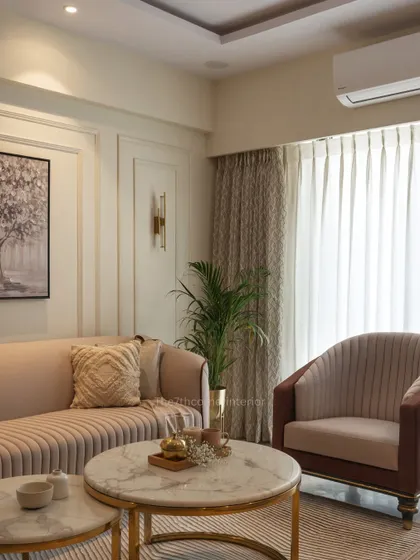 The living room ambiance of the 'Elysian Enclave' project, where a neutral color palette, elegant wall art, and marble-topped coffee tables with gold-finished legs create a warm and inviting atmosphere.