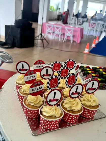 A close-up of the vanilla cupcakes with custom toppers for Reyan's first birthday. The toppers feature little race cars and checkered flags, tying into the Dinky Party theme perfectly.