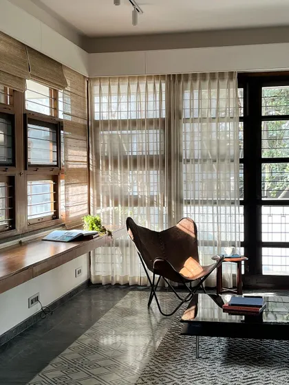 We created this cozy reading corner with a built-in wooden window seat. The butterfly chair and large windows, filtered by sheer curtains, make it a perfect spot to relax with a book in the afternoon sun.