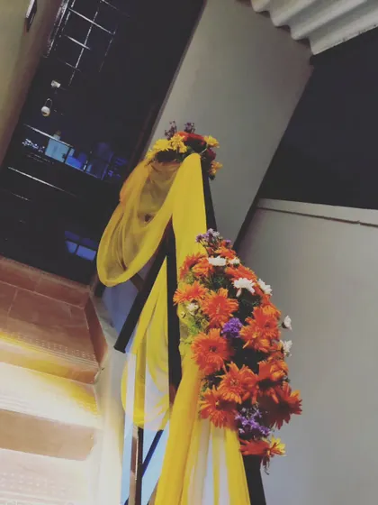 The festive decorations continue inside the home. Here, we've decorated the staircase railing with bright yellow fabric and fresh flower bouquets to carry the celebratory theme throughout the house.