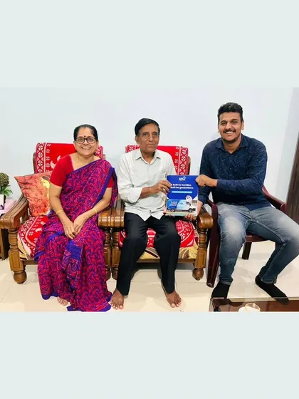 An elderly couple with our team member, holding our solar guide.
