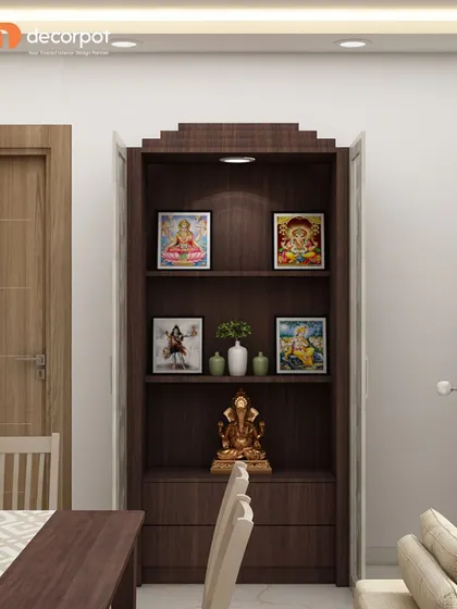 A simple yet elegant bookshelf-style pooja unit. The dark wood finish and single spotlight create a focused and reverent space for prayer and reflection.