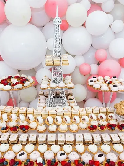 This stunning dessert table, complete with an Eiffel Tower centerpiece and a balloon wall, is an example of a themed setup I can create for a baby shower or any other special party.