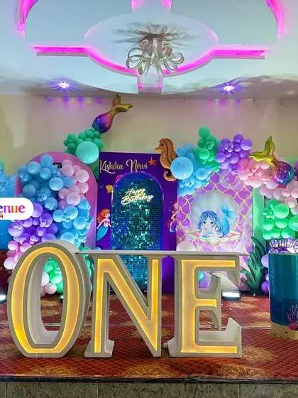 We dive deep into themes to create immersive worlds for your child's birthday. This vibrant mermaid-themed party features a large 'ONE' marquee sign, an under-the-sea backdrop with a shimmer wall, custom character prints, and balloon arrangements in ocean colors to complete the look.