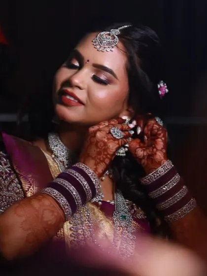 A close-up of the bride getting ready, her beautiful mehendi visible as she puts on her jewelry.