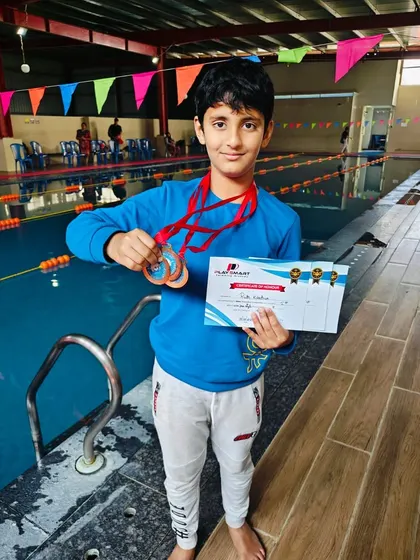 Saptarshi Paul proudly displays his gold and silver medals won at the Play Smart Swimming Academy competition, a testament to his hard work.
