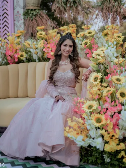 A beautiful portrait of the bride seated amidst a garden of sunflowers at her Haldi carnival.