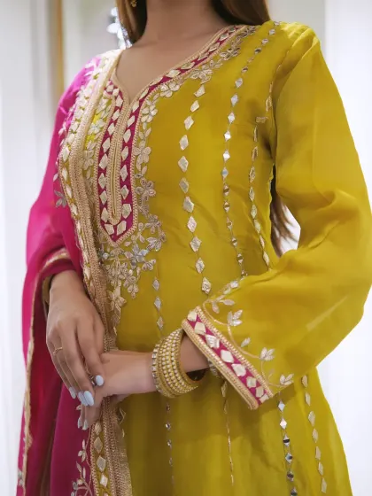 Colors and outfits that speak louder than words. A close-up of this beautiful yellow suit with pink accents and mirror work.