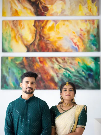 A formal engagement portrait against a backdrop of abstract art. The couple's traditional attire contrasts beautifully with the modern setting.