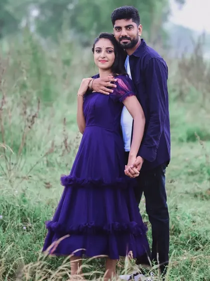 A couple enjoying a walk in nature for their pre-wedding shoot. The woman is wearing a lovely tiered purple dress from my rental collection, which is both comfortable and stylish.