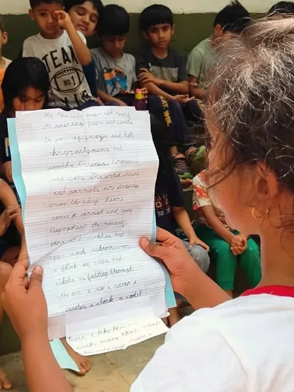 A child reads a poem she has written to the entire school during our "Poem in Your Pocket" day. We celebrate poetry as a way to capture feelings and observations, and the children share their work with courage and pride.