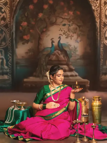 A moment of tranquility and light. The mother-to-be holds a traditional diya, its warm glow illuminating her face. This shot, set against a painted backdrop of peacocks, is rich with cultural and artistic meaning.