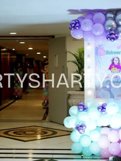 A fun welcome area for a mermaid and Baby Shark party, featuring a character cutout and a welcome poster framed by a colorful balloon arrangement.