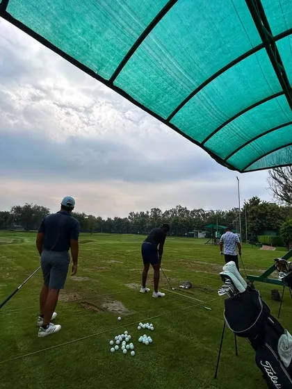 A group of friends practicing together under the cover of a bay, with a pile of golf balls ready for the session.