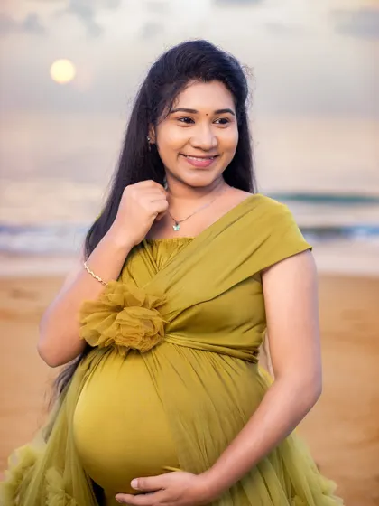 A beautiful, happy portrait of the mom-to-be, her joy shining as brightly as the sun rising over the ocean.