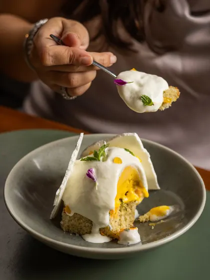 A guest enjoying a spoonful of the Tropical Pavlova, a perfect bite of cake, sorbet, and cream.