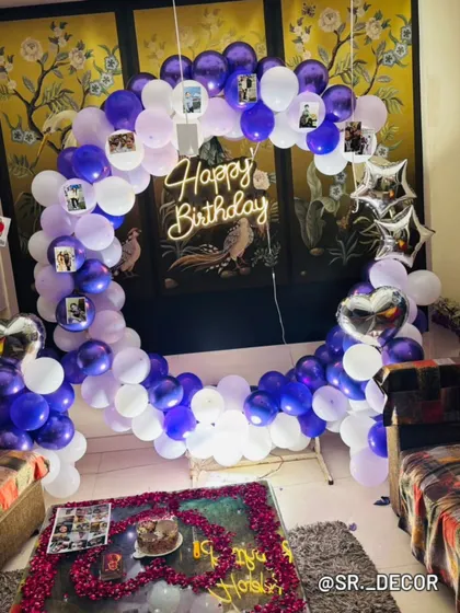 A wider view of the 18th birthday room decor, showing the balloon ring and a heart-shaped arrangement of petals on the table.