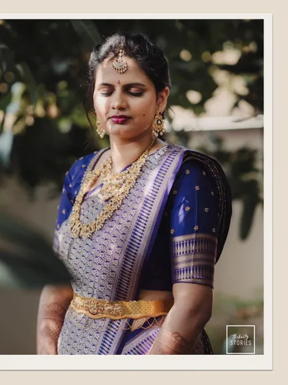 The bride in a royal blue saree, captured in a moment of quiet contemplation, showcasing her serene elegance.