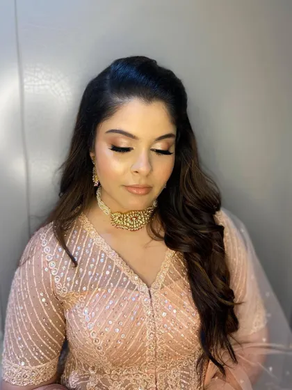 A close-up of the eye makeup, featuring a soft blend of peach and gold shimmer for a warm, inviting look.
