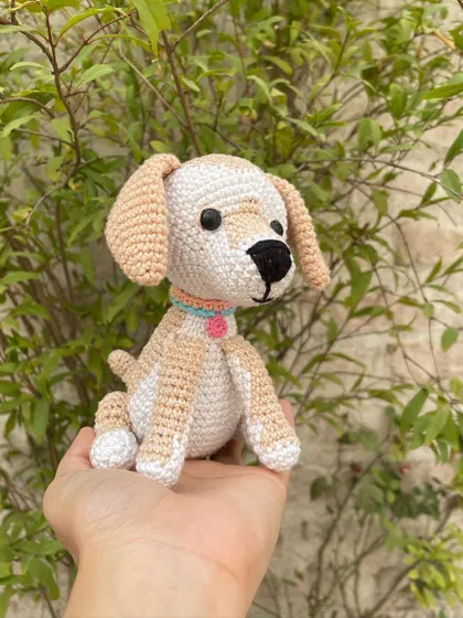 Here you can see the little tail and the posture of the handmade crochet dog. It's a small, palm-sized friend that can sit on a desk or shelf.