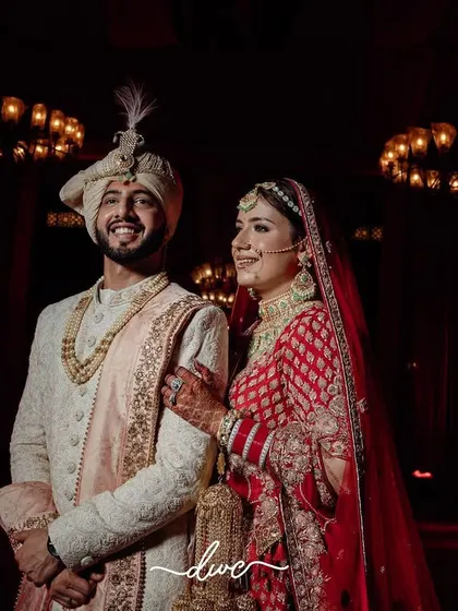 A classic wedding portrait of the bride and groom, standing together under the warm glow of chandeliers, smiling at the start of their journey.