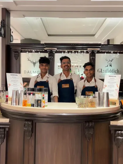 Our team of three bartenders ready for service behind a classic, elegant bar setup, showcasing their professional appearance and readiness.