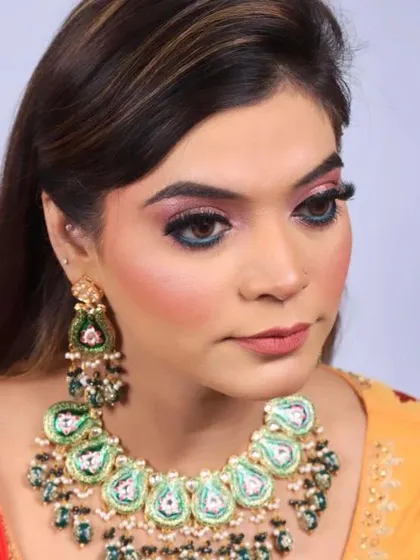 A detailed close-up of a vibrant party makeup look. This features a colorful pink and blue eyeshadow blend, sharp eyeliner, and long lashes, paired with a neutral pink lip.