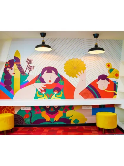 A creative breakout space with a built-in bench and vibrant wall art. The inclusion of power outlets makes this a functional spot for employees to work on their laptops in a more relaxed setting.