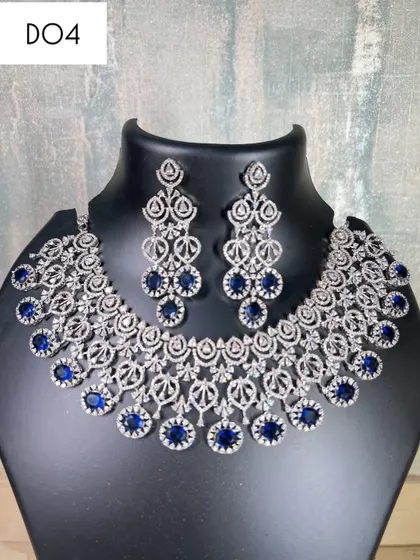 A still image of the sapphire blue and silver diamond necklace set. The design is elaborate and perfect for someone who wants a full, glamorous neckline.