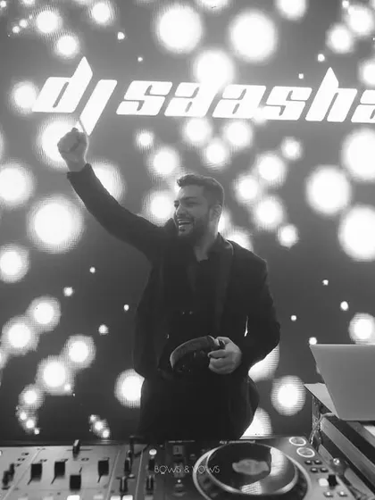 A moment of pure joy behind the decks. This black and white shot captures me in my element, with my logo lighting up the background. It's more than just playing music; it's about creating an unforgettable night.