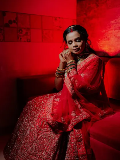 A full-length bridal portrait with dramatic red lighting, creating a moody and glamorous feel.