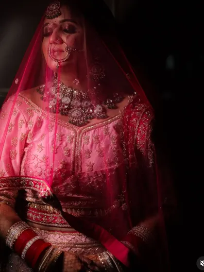 A moody and romantic shot of the bride under her veil. The lighting creates a soft, ethereal glow around her.