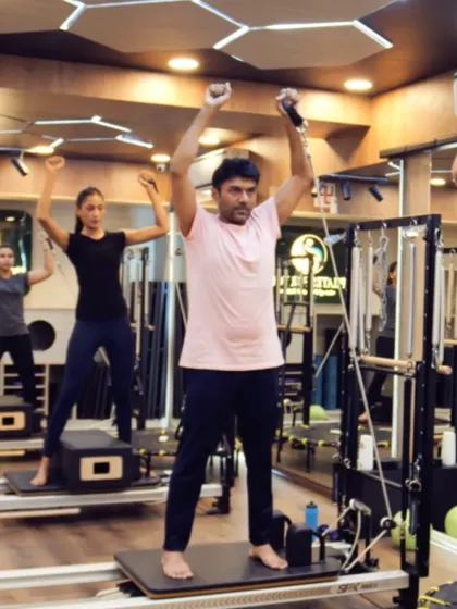 Here, clients use resistance straps for an upper body workout on the Reformer. This exercise strengthens the arms and shoulders while requiring core stability to maintain balance.