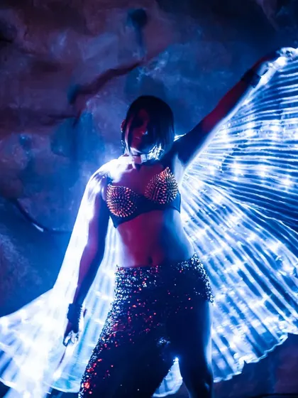 Another look at the LED wings from the show at Magique. The way the light reflects off the sequined skirt and rock-like background creates a stunning visual contrast.