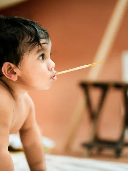 A tiny artist in thought. This creative milestone session captures the curiosity of a baby exploring new things, like a paintbrush.