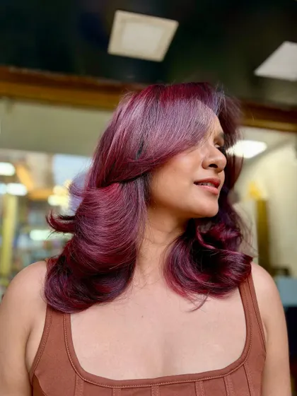 The final result of the red-violet balayage, styled with beautiful, bouncy curls to show off the dimension and shine.