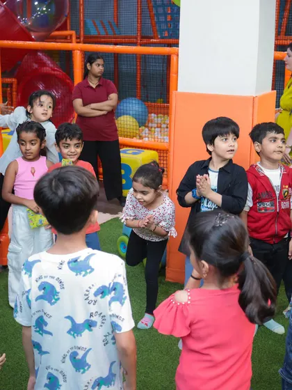 A group of children gathered in the play area, fully engaged in a party game. We organize activities to keep the energy high and the fun going.