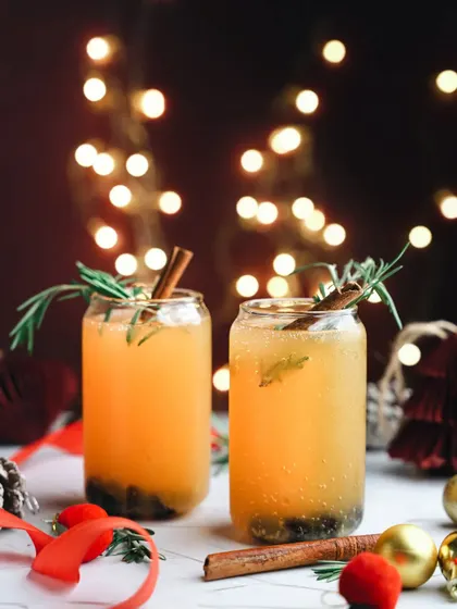 A warm, spiced Christmas drink with cinnamon and rosemary. The glowing lights in the background and festive props make this the perfect image for a holiday menu.