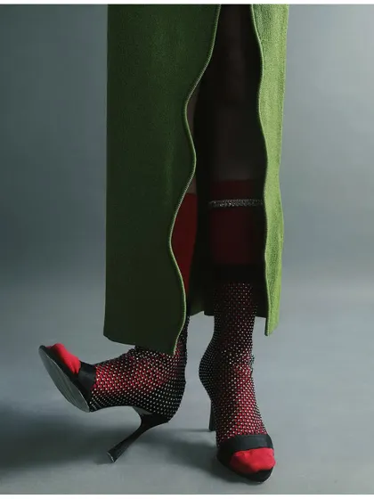 A creative detail shot focusing on the model's legs, showcasing layered socks and unconventional heels. This playful composition draws attention to the unexpected elements of the styling.