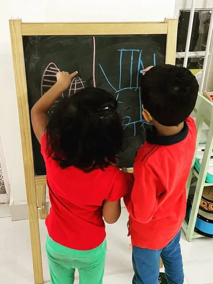 When two children wanted to use the blackboard at the same time, they came up with a brilliant solution: draw a line down the middle. This is a perfect example of how play teaches negotiation, problem-solving, and collaboration.