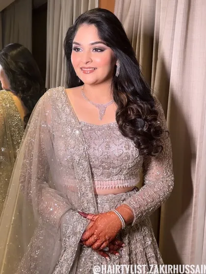 For this elegant evening look, I styled the hair in soft, open waves with a side part. This classic style complements the client's shimmery lehenga and diamond necklace perfectly.