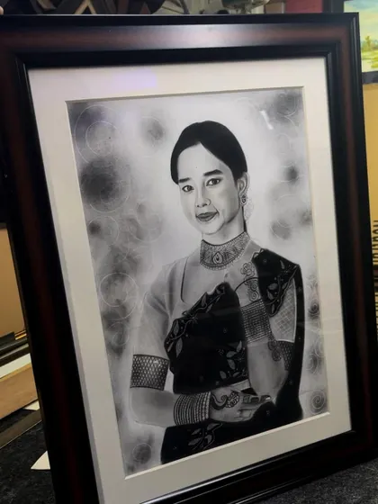 Another angle of the framed realistic portrait, showing how the dark wood frame complements the black and white artwork.