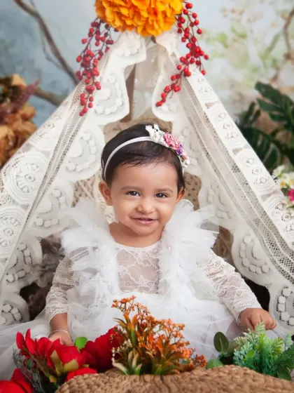 A beautiful smile from inside a lace teepee, surrounded by flowers. This boho-floral theme is so whimsical and perfect for a baby girl's milestone session.