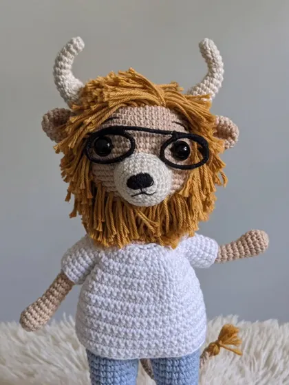 A close-up of the lion character wearing glasses, showing the detailed yarn work on his face and mane.